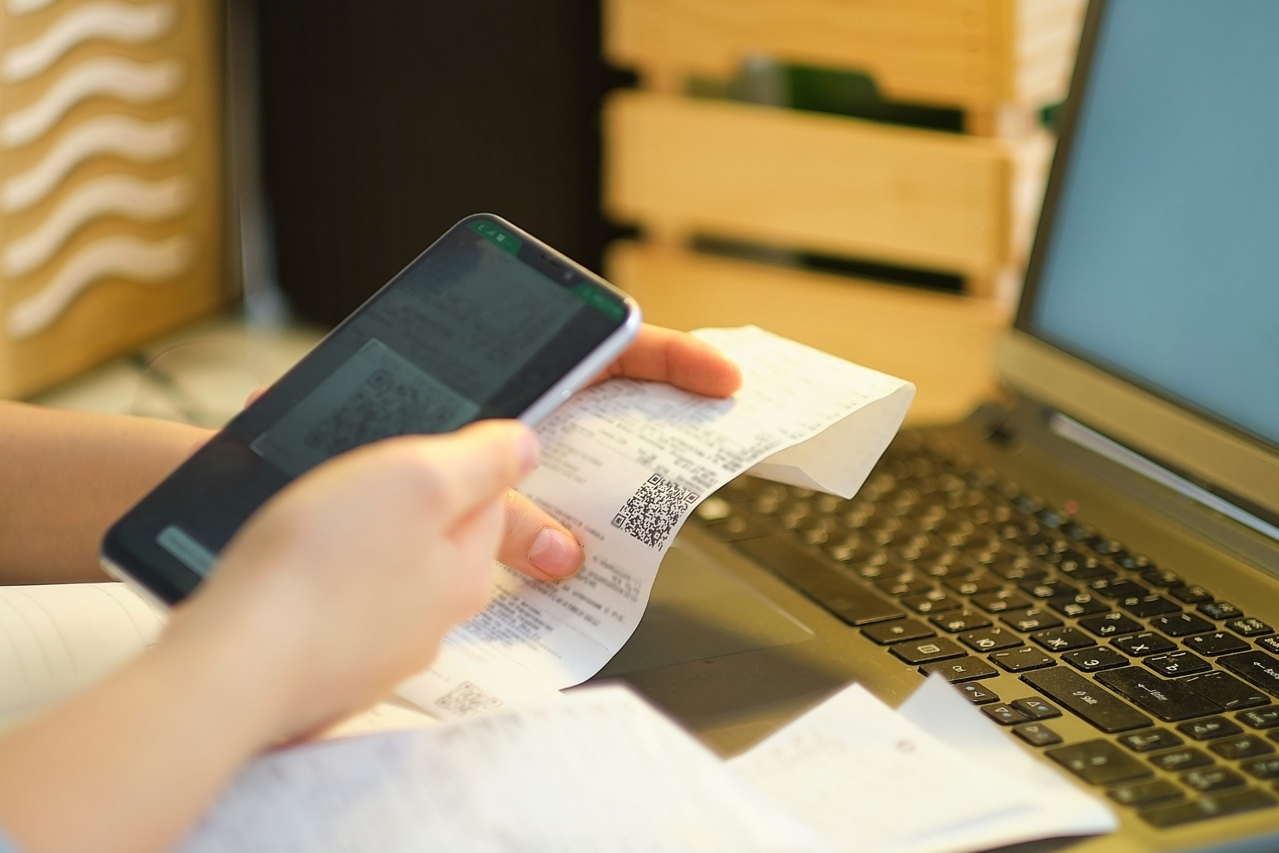 Unrecognizable Woman Scans Store Receipts Using A Smartphone - Contabilidade em Santa Catarina | Amaral Contabilidade